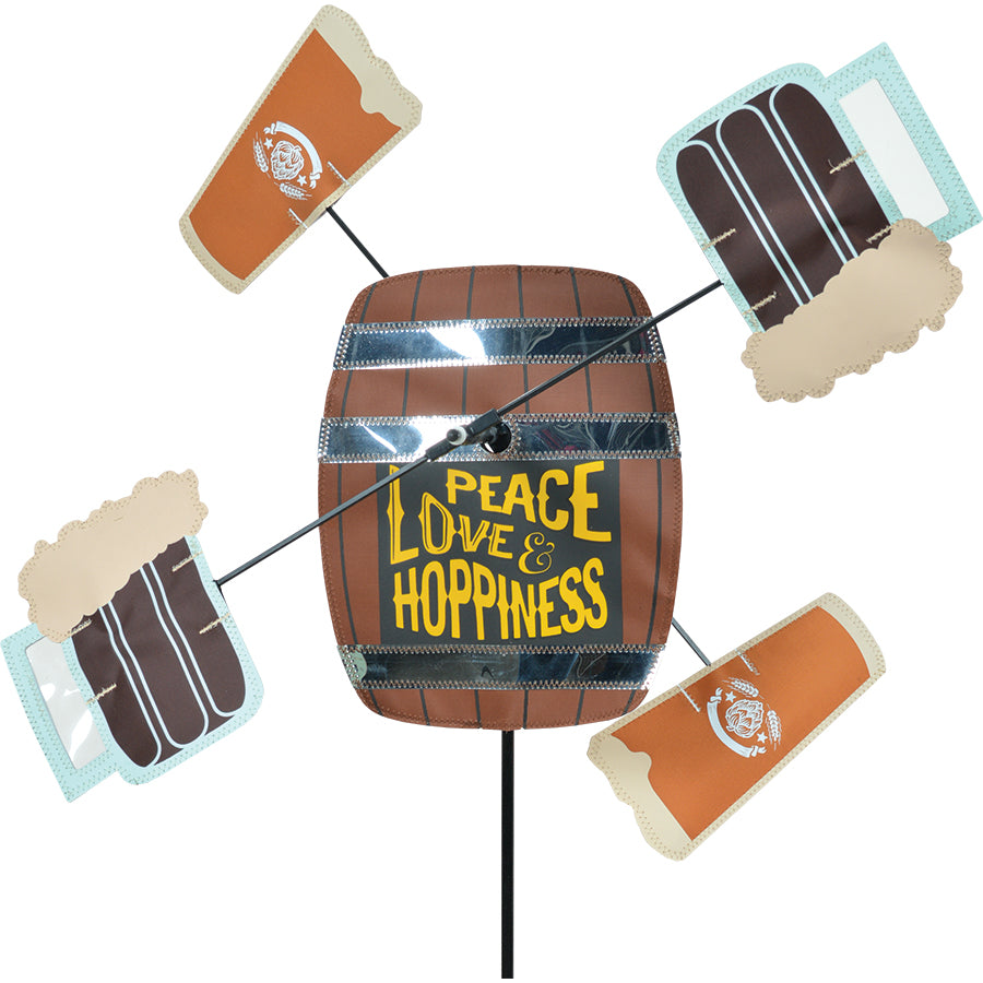 WhirliGig Spinner - Peace Love and Hoppiness displays vibrant colors outdoors, spinning gracefully in the wind against a backdrop of greenery.