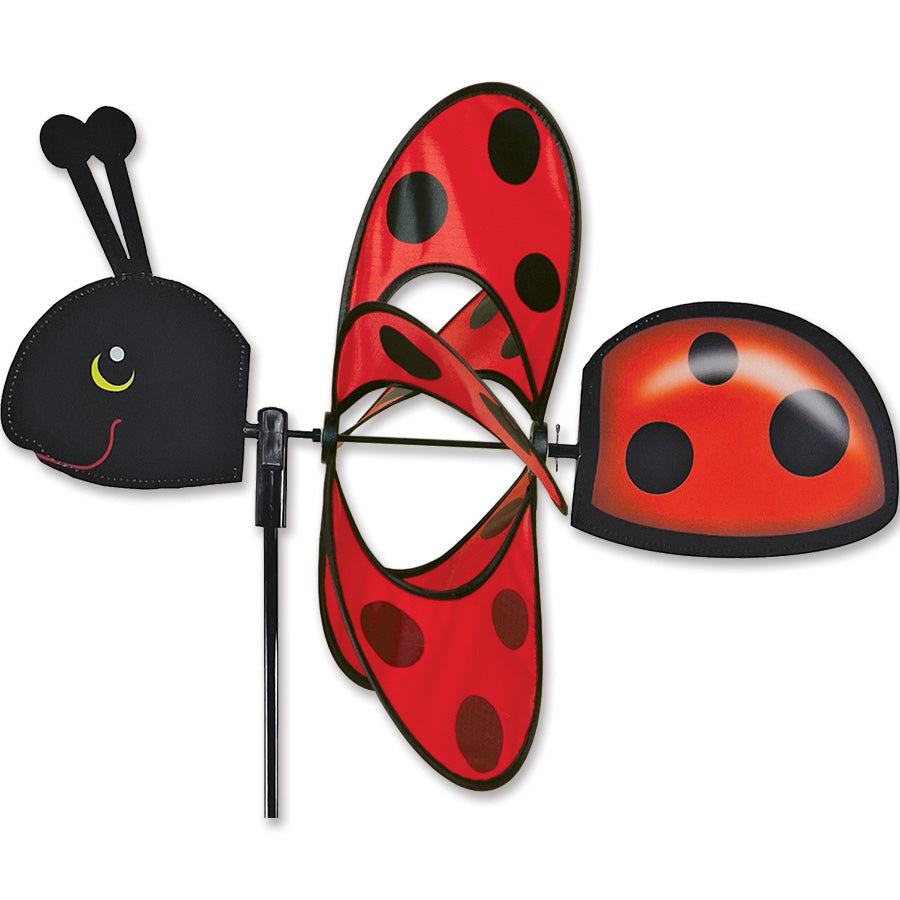 Ladybug Whirly Wing Spinner spinning in a garden, showcasing its colorful design and charming movement in the breeze.