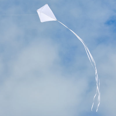 White Colorfly 30-inch diamond kite soaring in a clear blue sky with three colorful tails trailing behind, showcasing its vibrant design.