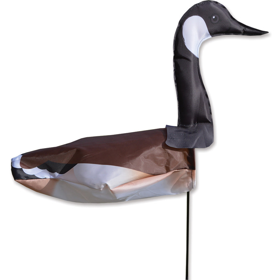 Windicator Canadian Goose weather vane swaying in the wind, attached to a fiberglass pole in an outdoor garden setting.
