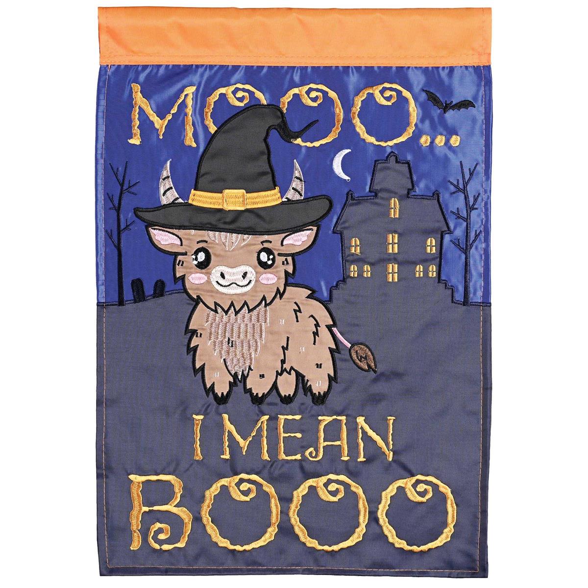 Witch Cow Moo I Mean Boo garden flag with whimsical cow wearing a witch hat displayed outdoors in a garden setting, double-sided design.