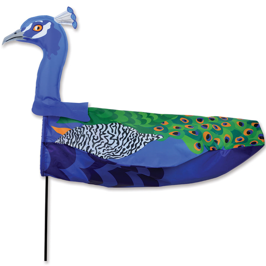 XL Windicator Weather Vane featuring a colorful peacock design inflating with the wind, set in a garden with flowers in the background.